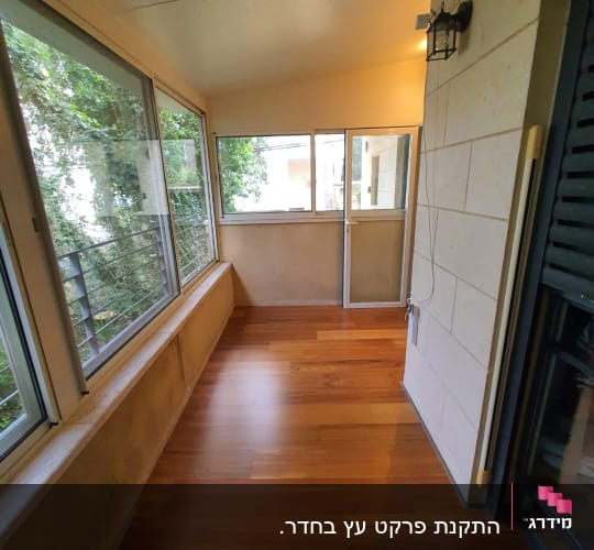רצפת פרקט עץ בחדר סגור עם חלונות גדולים